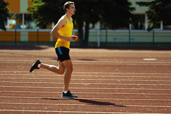 Jeune homme caucasien, athlète masculin, coureur pratiquant seul au stade public, terrain de sport ou piste de course à l'extérieur. Jeux de sport d'été. — Photo