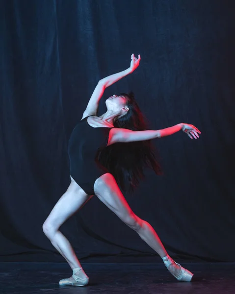 Giovane e graziosa ballerina in movimento isolata su sfondo scuro in luce al neon. Arte, movimento, azione, flessibilità, concetto di ispirazione. — Foto Stock