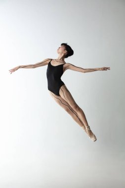 Genç ve zarif balerin, açık gri stüdyo arka planında izole edilmiş balerin. Sanat, hareket, eylem, esneklik, ilham kavramı.