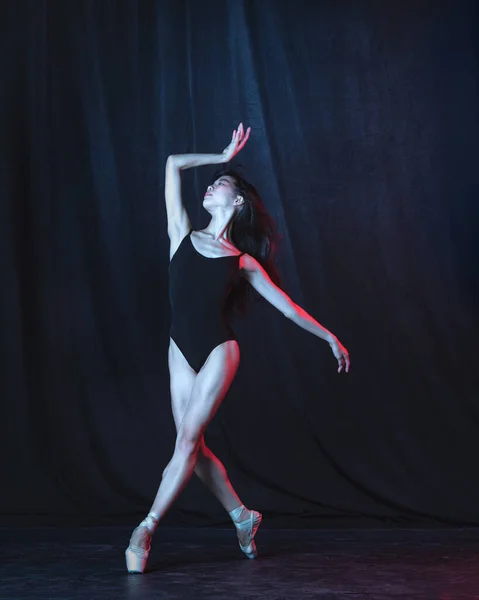 Dançarina de balé jovem e graciosa em movimento isolada em fundo escuro em luz de néon. Arte, movimento, ação, flexibilidade, conceito de inspiração. — Fotografia de Stock