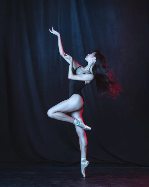 Молодая и грациозная балетная танцовщица в движении изолирована на тёмном фоне в неоновом свете. Искусство, движение, действие, гибкость, концепция вдохновения. — стоковое фото