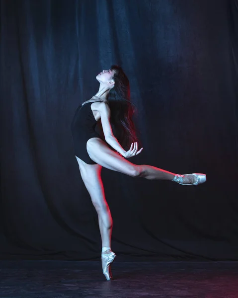 Young and graceful female ballet dancer in motion isolated on dark background in neon light. Art, motion, action, flexibility, inspiration concept. — Stock Photo, Image
