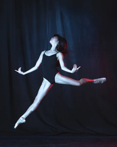 Молодая и грациозная балетная танцовщица в движении изолирована на тёмном фоне в неоновом свете. Искусство, движение, действие, гибкость, концепция вдохновения. — стоковое фото