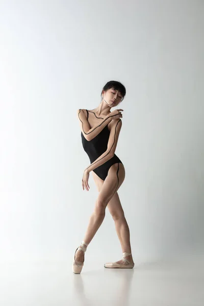 Joven y elegante bailarina de ballet, bailarina bailando aislada sobre fondo de estudio gris claro. Arte, movimiento, acción, flexibilidad, concepto de inspiración. — Foto de Stock