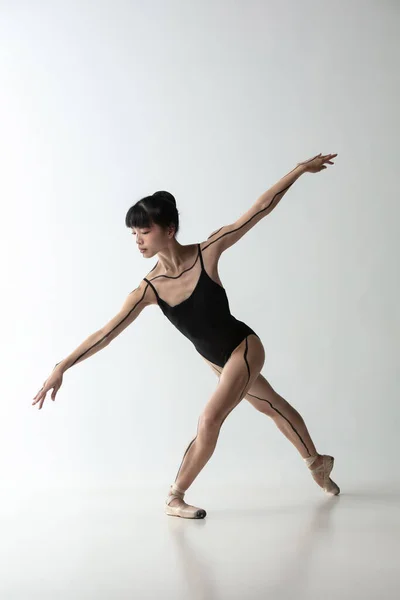 Una giovane e graziosa ballerina che danza isolata su uno sfondo grigio chiaro. Arte, movimento, azione, flessibilità, concetto di ispirazione. — Foto Stock