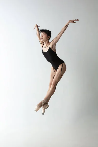 Ballerina giovane e graziosa, ballerina che balla isolata su uno sfondo grigio chiaro. Arte, movimento, azione, flessibilità, concetto di ispirazione. — Foto Stock