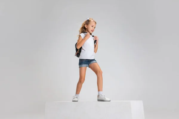 Повнометражний портрет усміхненої дівчини в повсякденному одязі, що стоїть на великій коробці ізольовано на білому фоні студії. Концепція щасливого дитинства . — стокове фото