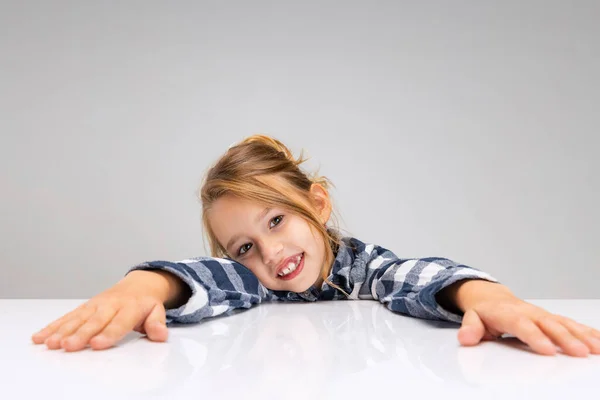 Retrato de menina bonita olhando para a câmera, fazendo rostos isolados no fundo do estúdio cinza. Emoções humanas, conceito de expressão facial. — Fotografia de Stock