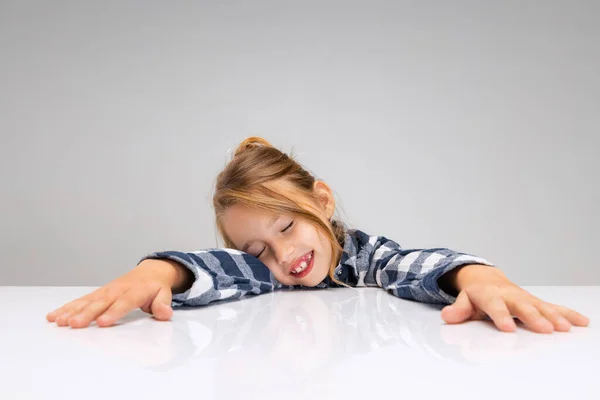 Portrét krásné holčičky, jak se dívá do kamery, dělá obličeje izolované na šedém pozadí studia. Lidské emoce, pojetí výrazu obličeje. — Stock fotografie