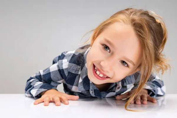 Close-up schattig mooi klein meisje kijken naar de camera, het maken van gezichten geïsoleerd op grijze studio achtergrond. Menselijke emoties, gezichtsuitdrukking concept. — Stockfoto