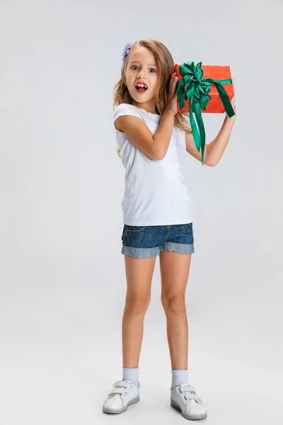 Досить кавказький портрет маленьких дівчаток, що стоїть з величезним подарунком, святкова коробка ізольована на сірому студійному фоні з копійкою для реклами — стокове фото