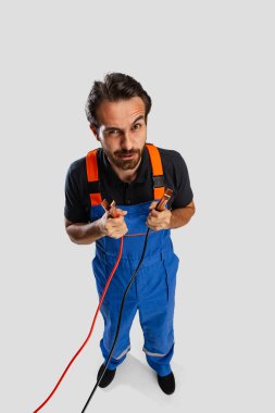 Genç bir adamın yüksek açılı görüntüsü, erkek oto tamircisi ya da beyaz stüdyo arka planında izole edilmiş iş aletleriyle eşofman üstleri..