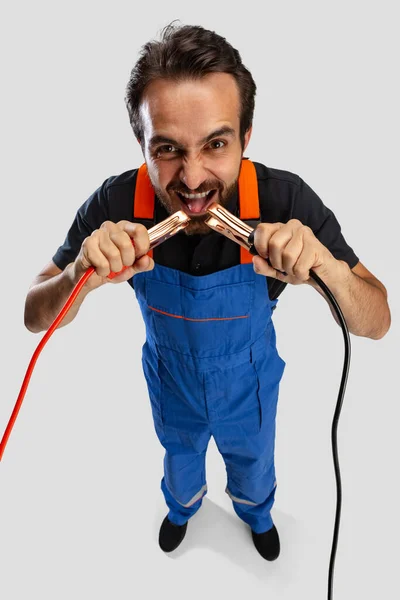 High angle view of young man, male auto mechanic or fitter in dungarees with work tools isolated over white studio background. — Stock Photo, Image