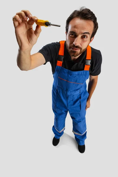 High angle view of young man, male auto mechanic or fitter in dungarees with work tools isolated over white studio background. — Stock Photo, Image