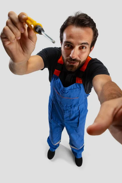 High angle view of young man, male auto mechanic or fitter in dungarees with work tools isolated over white studio background. — Stock Photo, Image