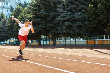 Kafkasyalı genç bir adam, erkek bir atlet, stadyumda tek başına antrenman yapan bir atlet, spor salonu ya da açık havada koşu pisti. Yaz sporu oyunları.