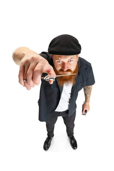 High angle view of red bearded man, barber or hair cutter in black cap isolated on white studio background. Holding his working equipment. — Stock Photo, Image