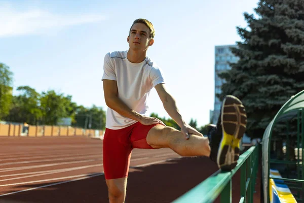 One young sportive man, male athlete, runner practicing alone before race at public stadium, sport court or running track, outdoors. Professional sport games.