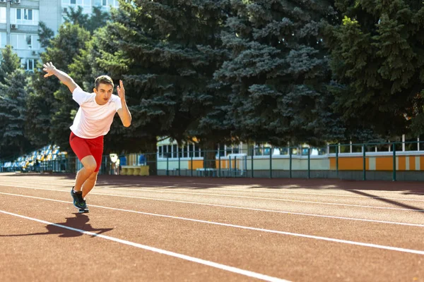 Young Caucasian man, male athlete, runner practicing alone at public stadium, sport court or running track outdoors. Summer sport games. — Stock Photo, Image