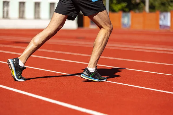 Image recadrée d'un athlète masculin, d'un coureur s'entraînant dans un stade public, un terrain de sport ou une piste de course à l'extérieur. Jeux de sport d'été. Mans jambes — Photo