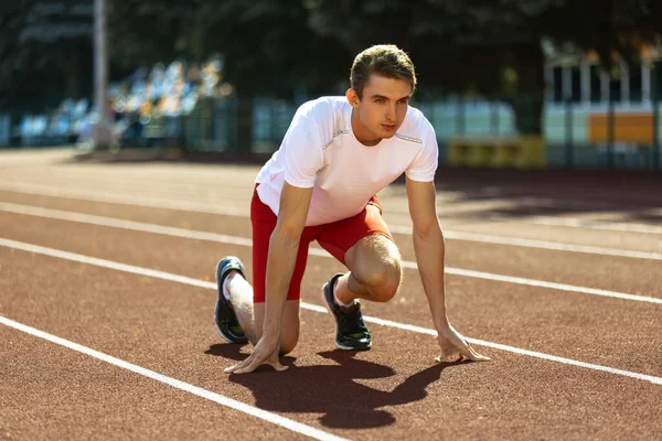 Un jeune sportif, athlète masculin, coureur pratiquant seul avant la course au stade public, au terrain de sport ou sur piste de course, à l'extérieur. Jeux de sport professionnel. — Photo