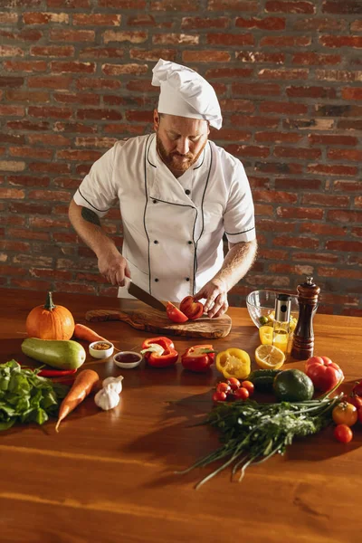 Giovane caucasico con la barba rossa, chef che cucina insalata di verdure fresche nel bar, cucina del ristorante. Concetto di una dieta corretta e sana. — Foto Stock