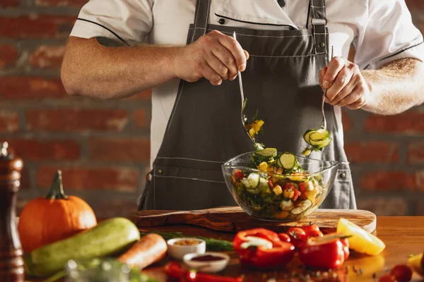 Ritratto ritagliato di chef maschile, cuoco che prepara insalata di verdure nel caffè, cucina del ristorante. Concetto di una dieta corretta e sana. — Foto Stock