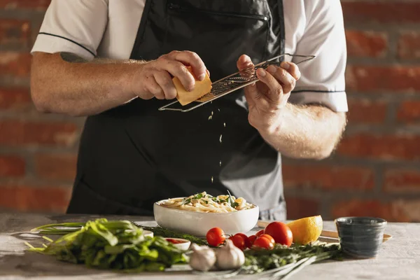 Cropped portrait of male chef, cook preparing carbonara in his cafe, restaurant kitchen. Concept of a correct, healthy diet. Tasting pasta — Stock Photo, Image