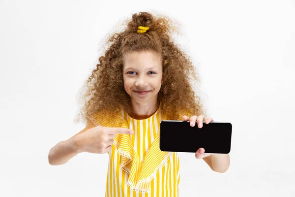 Πορτρέτο του μικρού Καυκάσιου κοριτσιού, παιδί που ποζάρει, δείχνοντας στο τηλέφωνο απομονωμένο σε λευκό φόντο. — Φωτογραφία Αρχείου