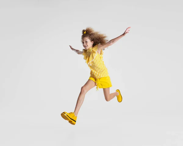 Portrait complet de petite fille préscolaire blanche active en tenue jaune vif et chaussures isolées sur fond blanc — Photo