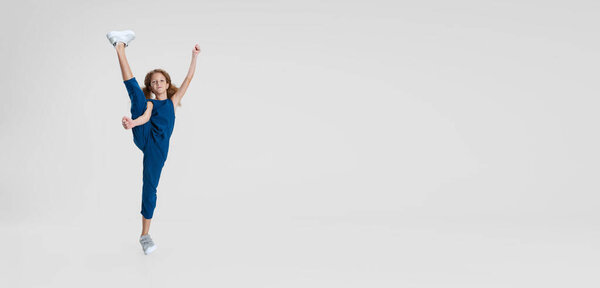 Flyer with little Caucasian cute curly beautiful girl in blue stylish jumpsuit stands in a twine isolated over white studio background. Leisure activity concept