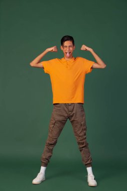 Yeşil vintage stüdyo arka planında izole edilmiş günlük giysiler içindeki genç bir adamın portresi. İnsan duyguları kavramı.