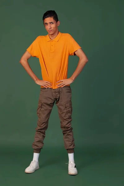 Portrait de jeune homme, étudiant en tenue décontractée posant isolé sur fond de studio vintage vert. Concept des émotions humaines. — Photo