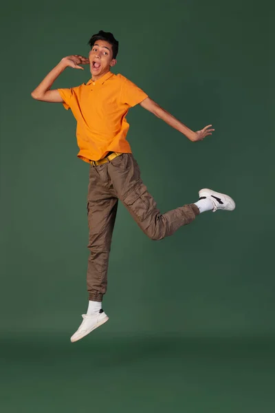 Portret van een jonge man, student in casual kleding springen geïsoleerd op groene vintage studio backgroud. Menselijke emoties concept. — Stockfoto