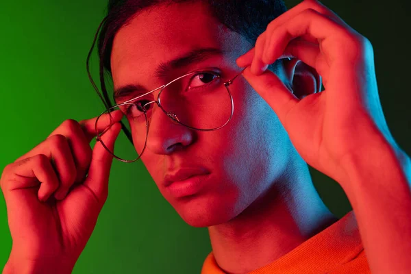 Retrato de close-up do jovem, estudante posando isolado no estúdio verde backgroud em luz de néon. Conceito de emoções humanas. — Fotografia de Stock