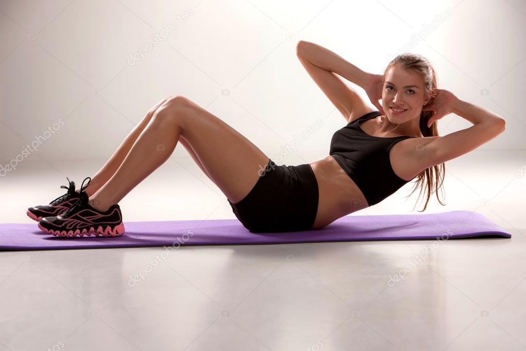 Attractive woman do fitness exercise on a lilac mat