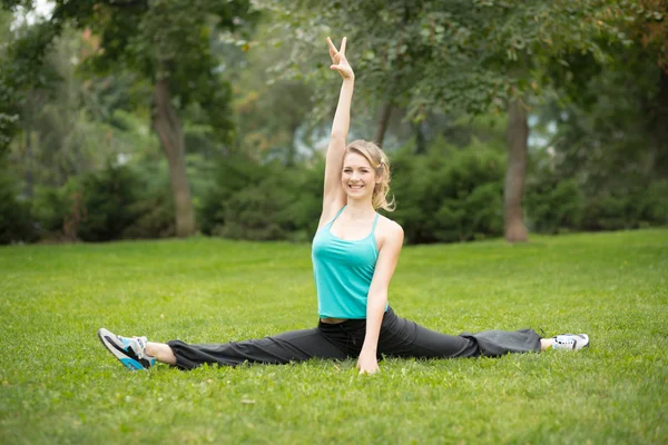 Belle jeune femme faisant des exercices d'étirement dans le parc . — Photo