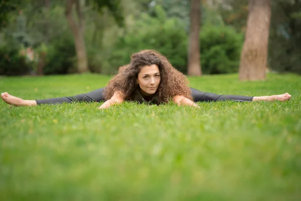 Belle jeune femme faisant des exercices d'étirement dans le parc . — Photo