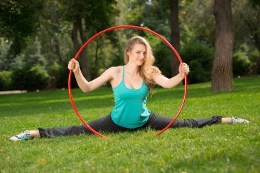 Young female athlete with hula hoop in the park clipart