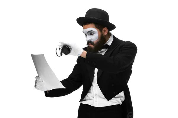 Man with a face mime reading through magnifying glass — Stock Photo, Image