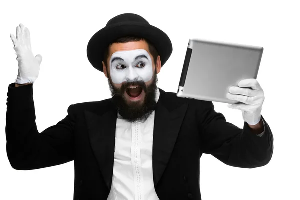 Человек с мимом на лице работает над ноутбуком — стоковое фото