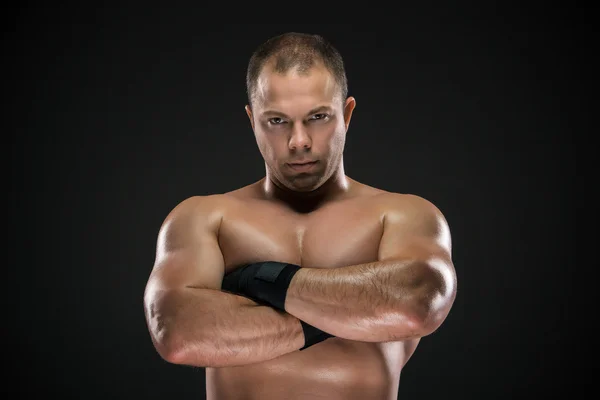 Studio portrait of young caucasian boxer with folded hands posing ark background — Stock Photo, Image