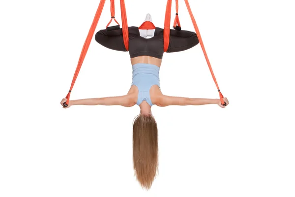 Mujer joven haciendo yoga aéreo anti-gravedad en hamaca sobre un fondo blanco sin costuras . —  Fotos de Stock