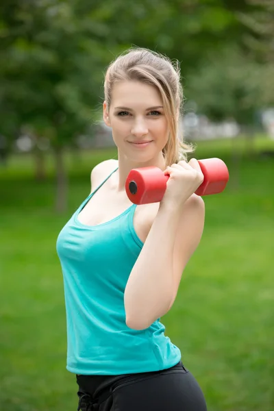 Sport meisje oefening met halters in het park — Stockfoto