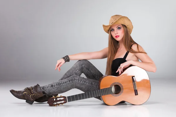 A menina bonita em um chapéu de cowboys e guitarra acústica . — Fotografia de Stock