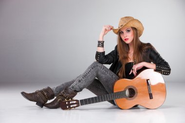 The beautiful girl in a cowboys hat and acoustic guitar.