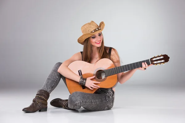 Bir kovboy şapkası ve akustik gitar güzel kız. — Stok fotoğraf