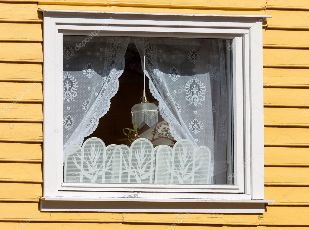 window in a wooden house with white curtains