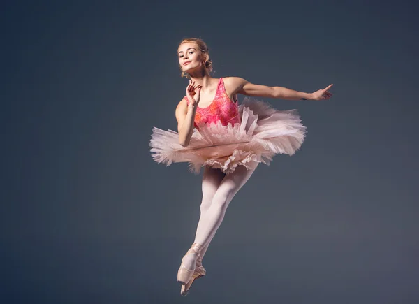 灰色の背景に美しい女性バレエ ダンサー。バレリーナが身に着けているピンクのチュチュとポワント シューズ. — ストック写真