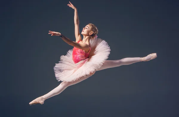 灰色の背景に美しい女性バレエ ダンサー。バレリーナが身に着けているピンクのチュチュとポワント シューズ. — ストック写真